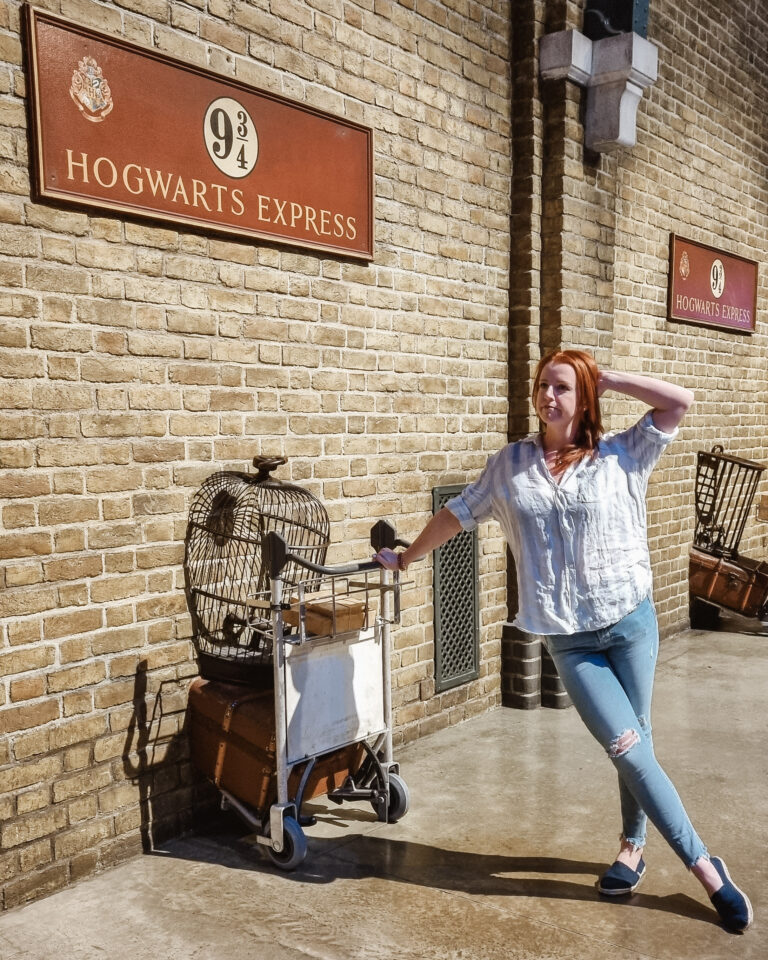 A woman leaning against a trolley at Hogwarts Express platform