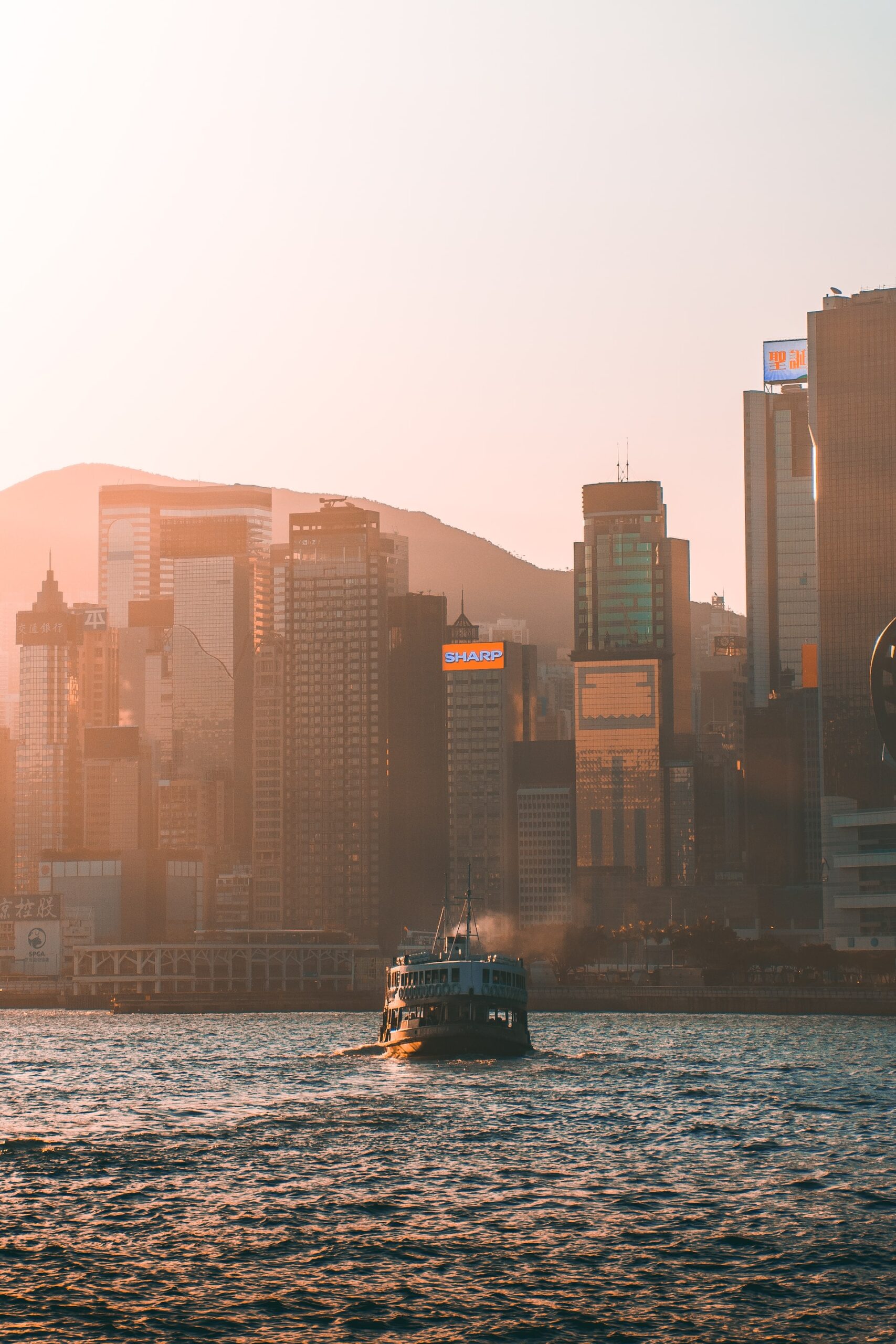 Hong Kong harbour with the skyline in background and star ferry on the water a sunset