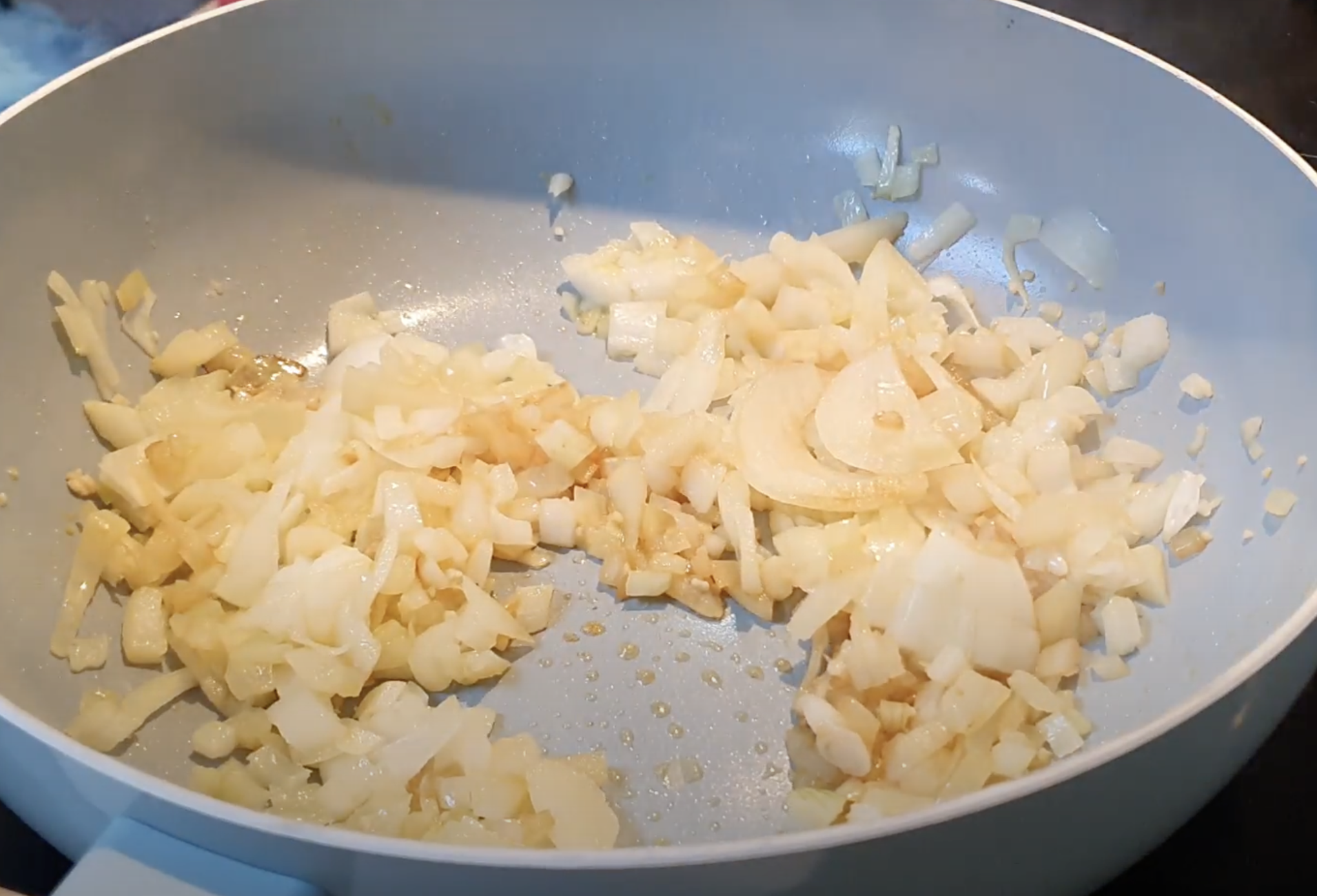 Blue frying pan with onion cooking